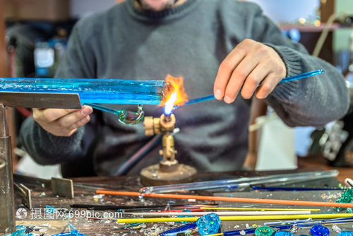 手工艺人用品的在集市上制作玻璃标本Glass制造商用燃烧的火炬制成熔化玻璃将喷灯的火焰贴近新玻璃艺术品手工人在品集市上制作玻璃标
